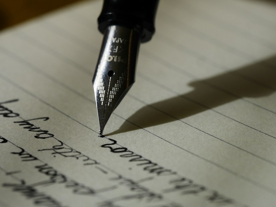 A fountain pen touching a handwritten notebook page